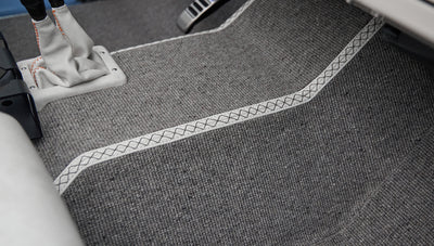 Gray carpeted floor with white leather trim and orange stitching around gear shift area inside Classic Ford Bronco