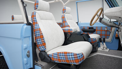 Interior of Classic Ford Bronco with white seats featuring blue and orange plaid accents