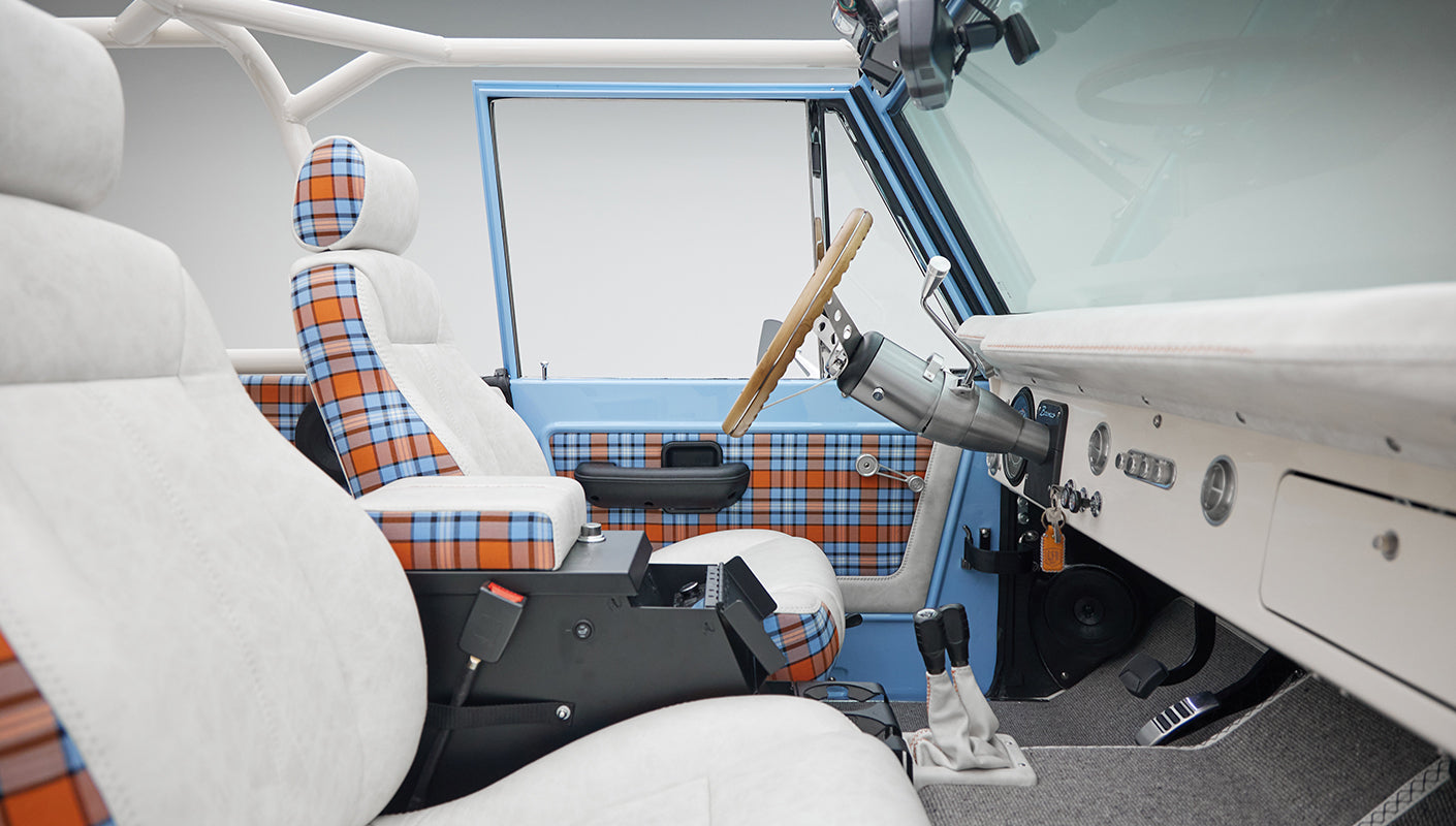 Side view of Classic Ford Bronco interior showing dashboard and seats with white and plaid covers