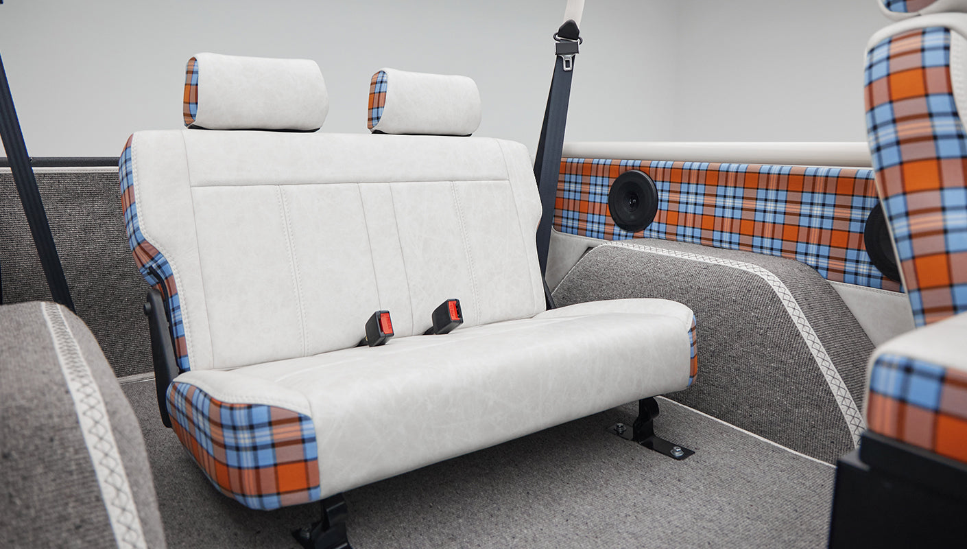 Classic Ford Bronco rear bench seat with white and plaid upholstery and roll cage bars