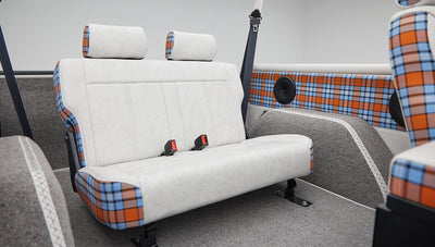 Classic Ford Bronco rear bench seat with white and plaid upholstery and roll cage bars
