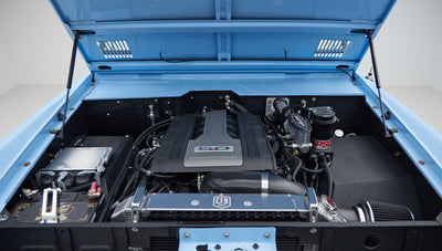 Wide view of engine bay with 5.0 engine and various components inside blue Classic Ford Bronco