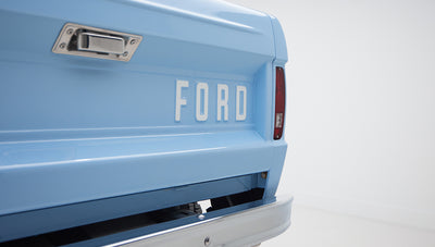 Rear corner of a Wind Blue Classic Ford Bronco with Ford lettering on the tailgate