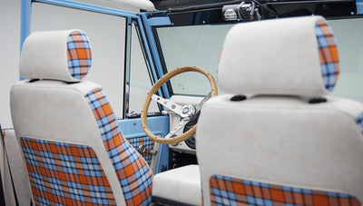 Front seats and steering wheel inside a Classic Ford Bronco with plaid upholstery details