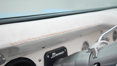 White leather dashboard cover with orange stitching and vintage Bronco emblem on Classic Ford Bronco