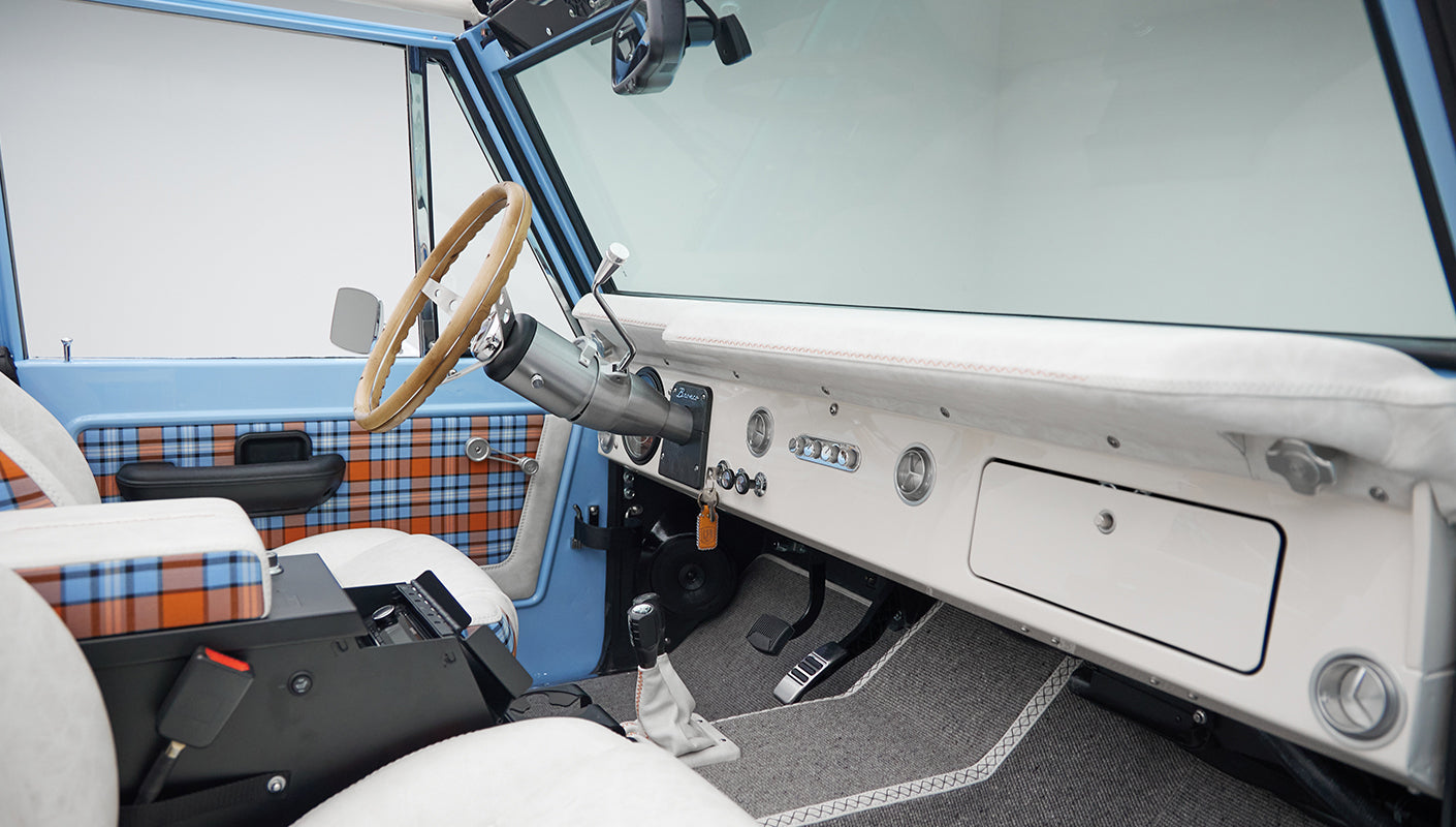 Blue and orange plaid door panel with black handle and chrome window crank inside Classic Ford Bronco