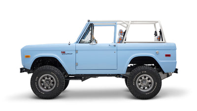 Classic Ford Bronco side profile in light blue with white roll bar and plaid seat covers