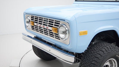 Close-up of front grille and round headlights of light blue Classic Ford Bronco