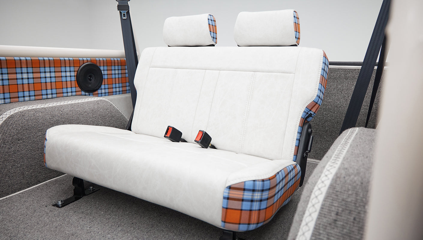 Rear passenger bench seat in Classic Ford Bronco with white upholstery and plaid detailing