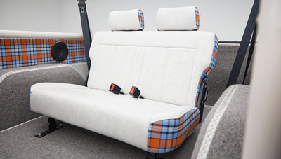 Rear passenger bench seat in Classic Ford Bronco with white upholstery and plaid detailing