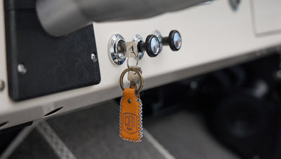 Classic Ford Bronco dashboard showing key in ignition with orange leather keychain and control knobs