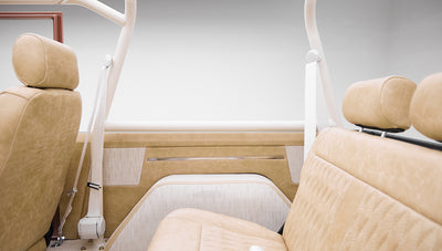 Rear passenger seat and beige door panel of a Classic Ford Bronco with roll cage