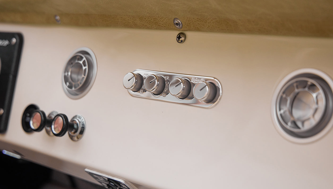 Close-up of beige dashboard with vintage style climate control knobs and air vent in Classic Ford Bronco