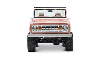Classic Ford Bronco in pinkish paloma color with white roll cage, front view on white background