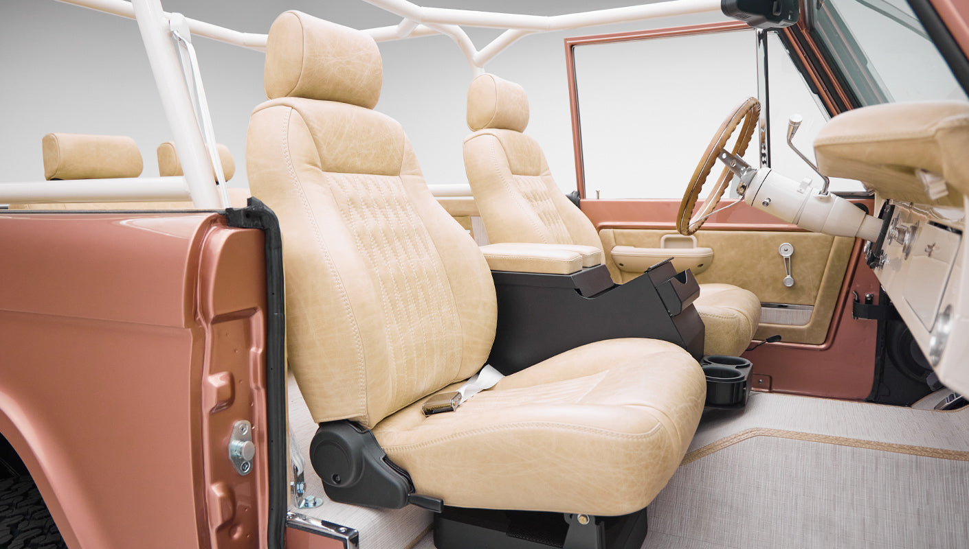 Interior view of Classic Ford Bronco showing beige leather front seats and open door