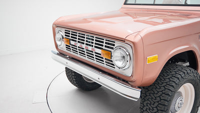Front section of a Classic Ford Bronco with pinkish exterior and chrome bumper