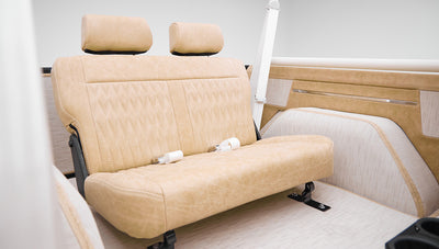 Rear bench seat inside Classic Ford Bronco with beige upholstery and seat belts