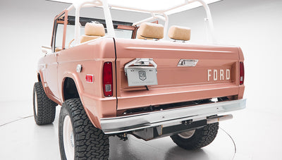 Rear view of a bronze Classic Ford Bronco showing the tailgate, bumper, and roll cage