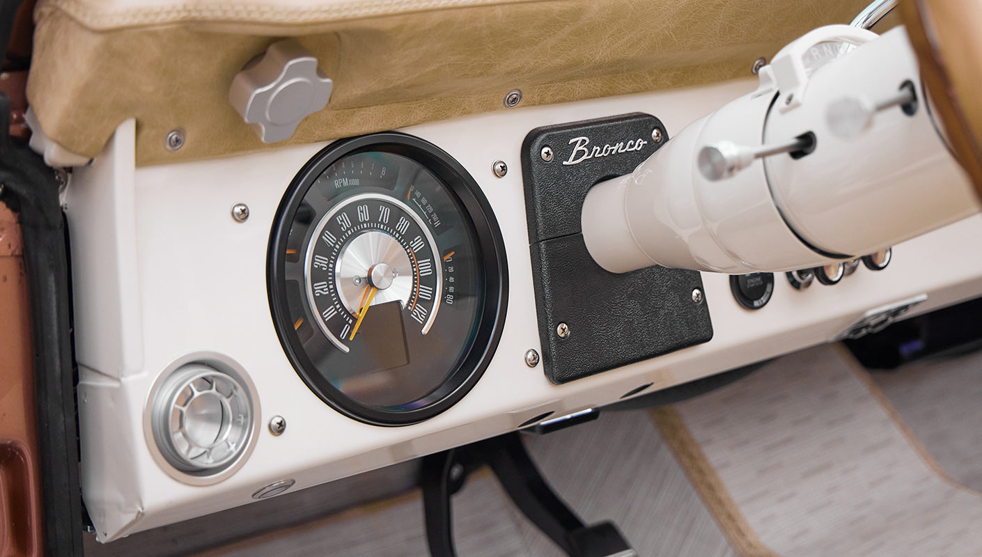 Classic Ford Bronco dashboard with speedometer and black Bronco emblem