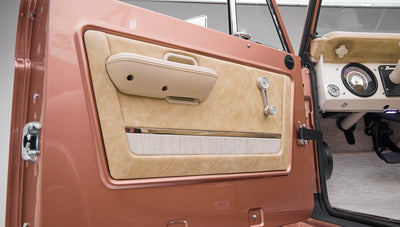 Beige door panel with armrest and window crank inside a Classic Ford Bronco vehicle