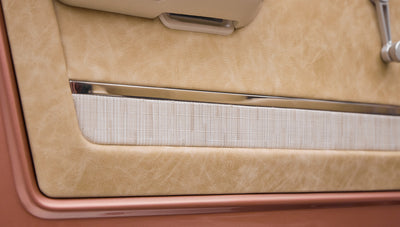 Close-up of textured beige upholstery and fabric insert on a Classic Ford Bronco door panel