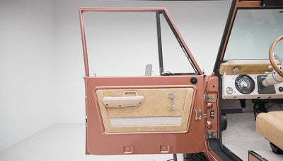 Open driver side door with beige interior panel of a Classic Ford Bronco