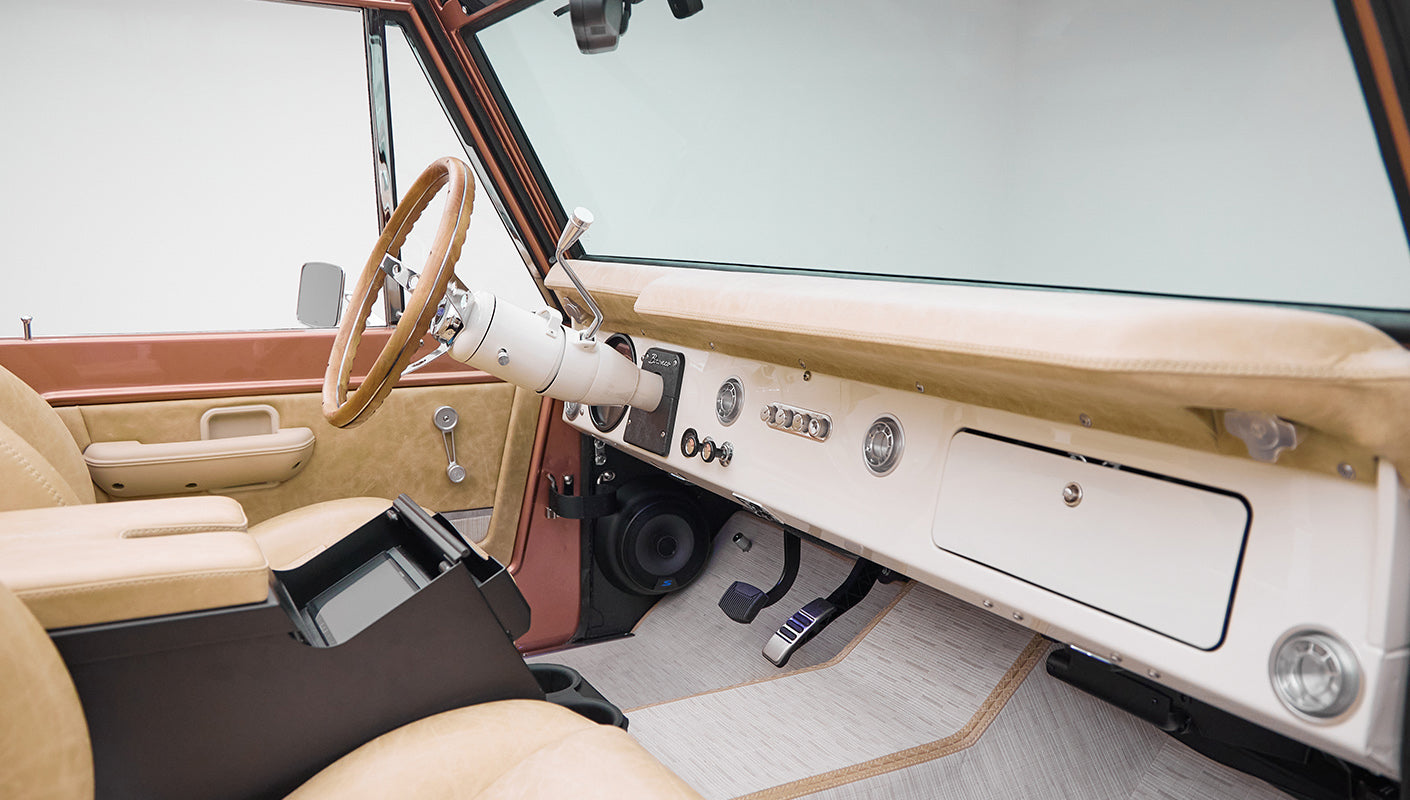 Classic Ford Bronco interior with beige seats and dashboard with steering wheel