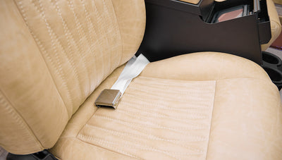 Beige leather front seat with metal seatbelt buckle and cup holders in Classic Ford Bronco