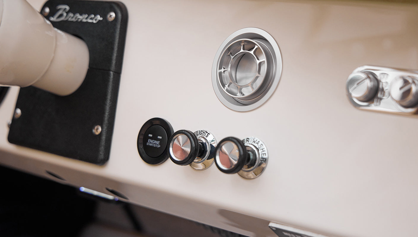Close-up of Classic Ford Bronco dashboard controls including engine start button and knobs