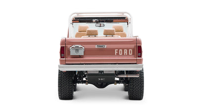 Classic Ford Bronco in pinkish paloma color with white roll cage, rear view on white background
