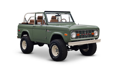 Green Classic Ford Bronco angled showing front and passenger side, with tan leather interior visible