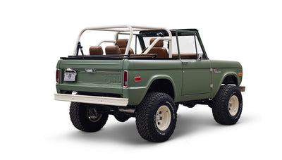 Angled rear view of green Classic Ford Bronco with tall off-road tires and white wheels