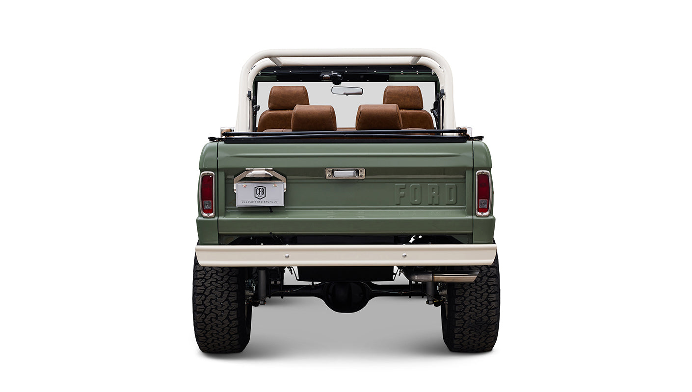 Rear view of Classic Ford Bronco in boxwood green showing tailgate, brown seats, and white bumper.