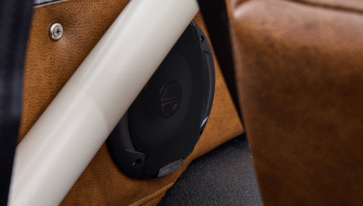 Black Alpine speaker mounted on brown leather trim inside Classic Ford Bronco door panel