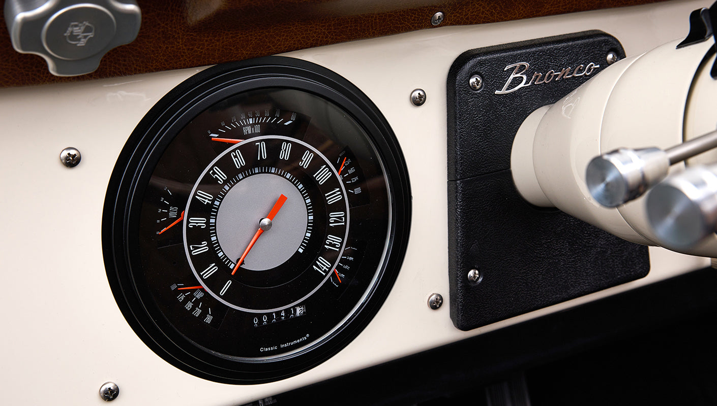 Speedometer and tachometer gauge cluster with Bronco emblem on dashboard inside Classic Ford Bronco
