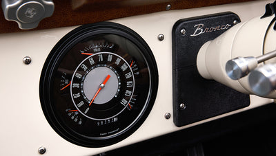 Speedometer and tachometer gauge cluster with Bronco emblem on dashboard inside Classic Ford Bronco