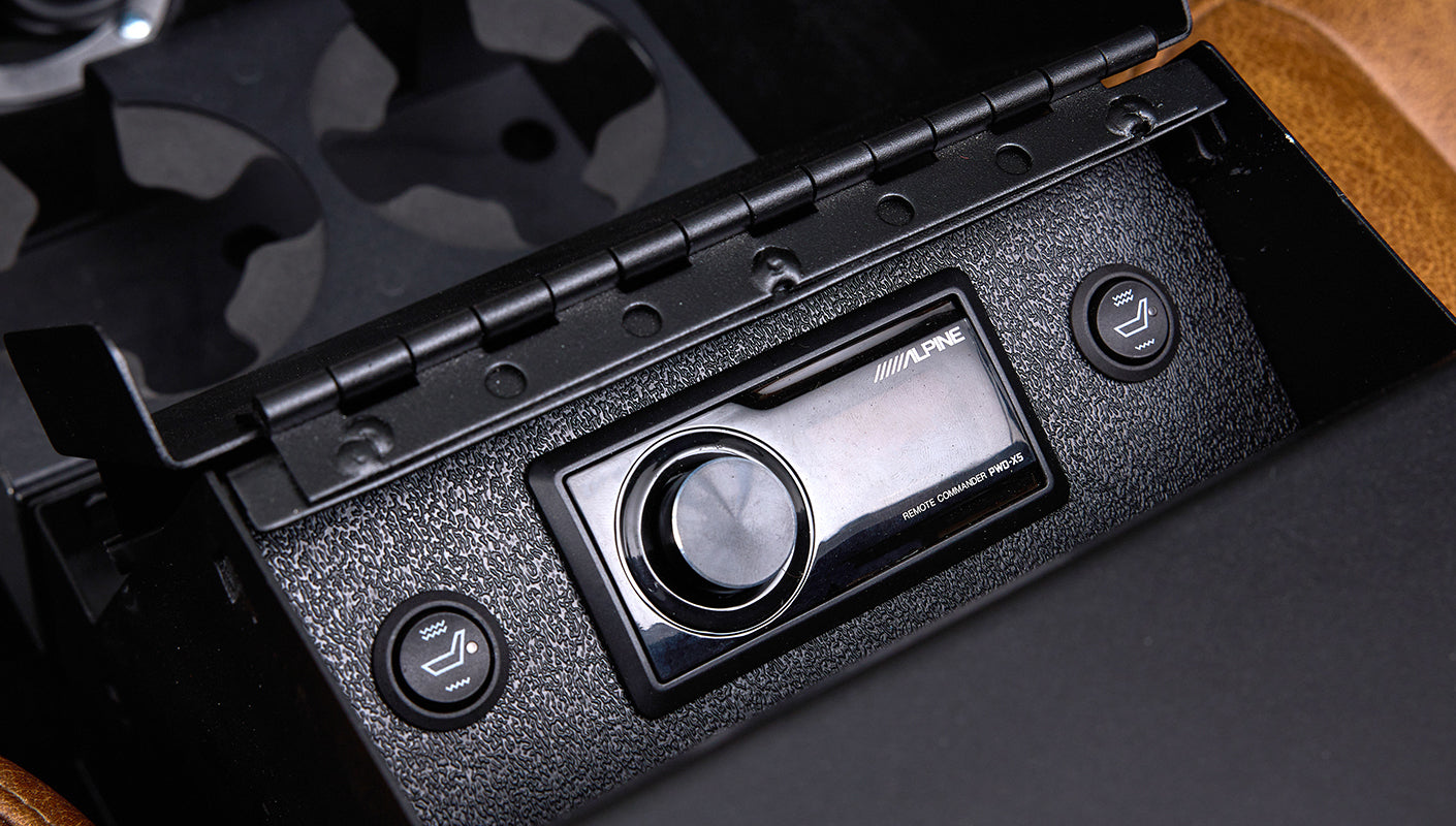 Black Alpine remote commander and heated seat buttons in storage compartment inside Classic Ford Bronco