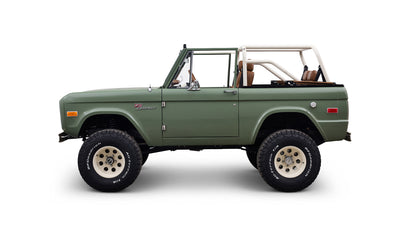 Side profile of green Classic Ford Bronco with two doors and off-road tires on white background
