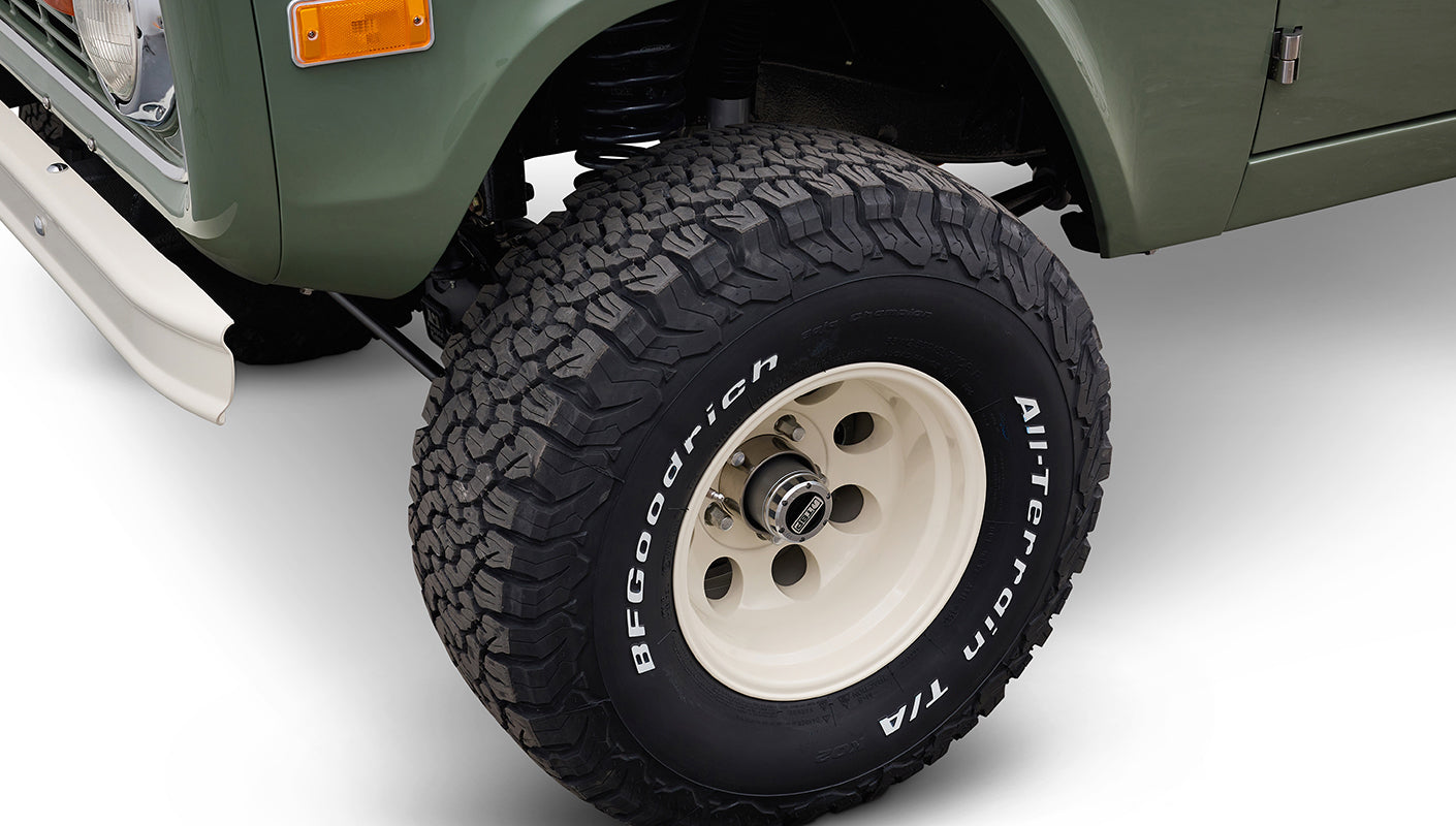Close-up of BFGoodrich All-Terrain tire and cream rim on green Classic Ford Bronco