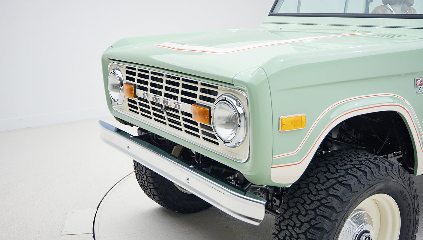 Close-up detail of front grille, headlights, and bumper of Classic Ford Bronco in porcelain green