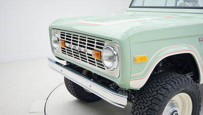 Close-up detail of front grille, headlights, and bumper of Classic Ford Bronco in porcelain green