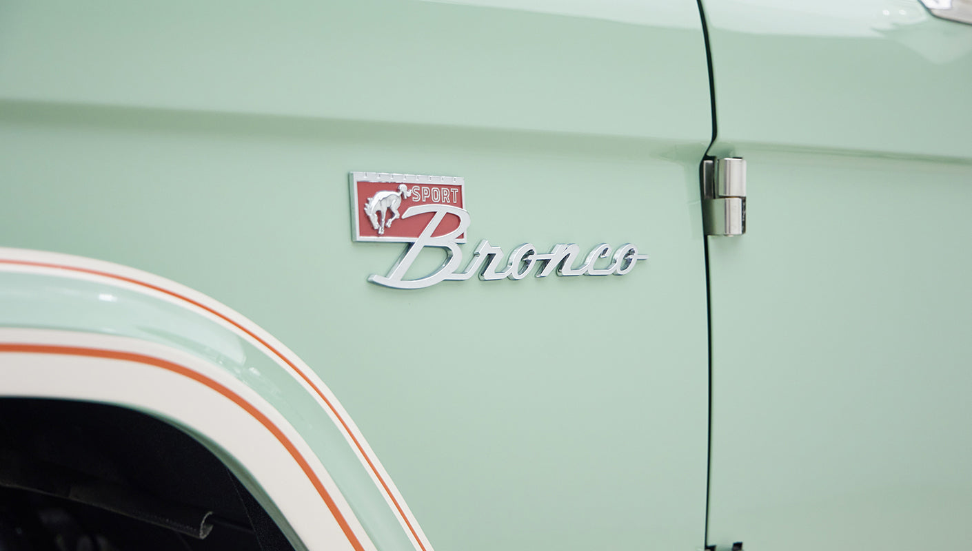 Close-up of Sport Bronco emblem on porcelain green classic Ford Bronco with white and orange trim