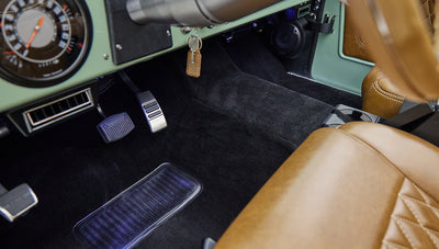 Foot pedals and lower dashboard area with tan leather seat inside classic Ford Bronco