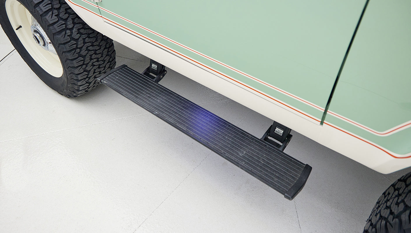 Extended black side step running board below pale green door of Classic Ford Bronco