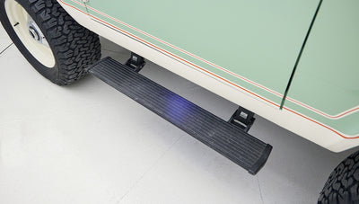 Extended black side step running board below pale green door of Classic Ford Bronco