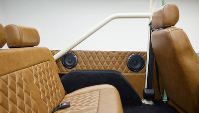 Rear interior seating area with brown leather, diamond stitching, and two black round speakers