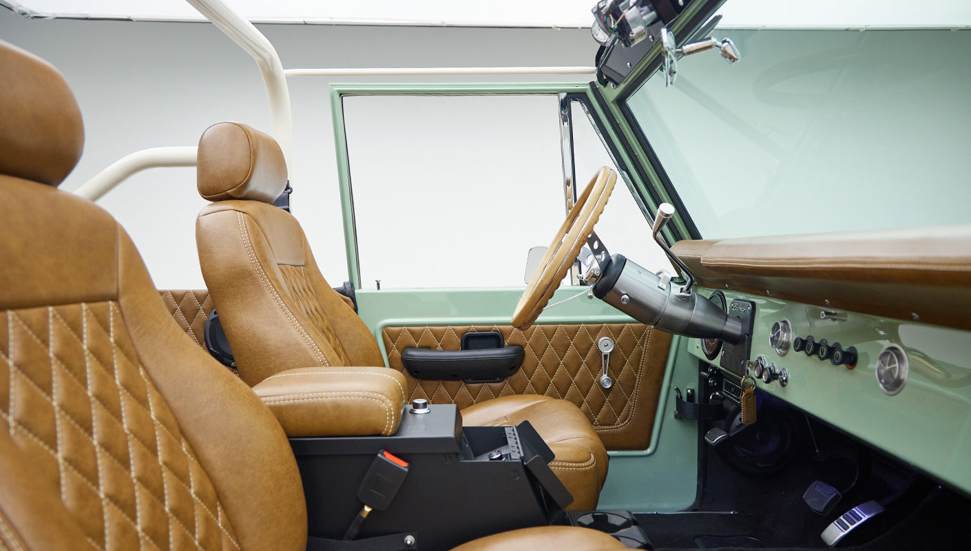 Front interior side view showing tan leather seats and matching steering wheel inside Classic Ford Bronco