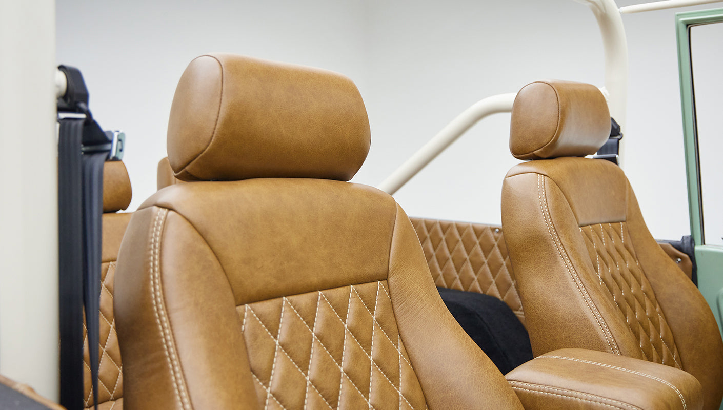 Close-up front seats featuring tan leather upholstery with diamond stitching and center armrest