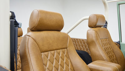 Close-up front seats featuring tan leather upholstery with diamond stitching and center armrest