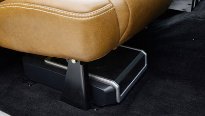 Speaker and audio equipment under front passenger seat covered with tan leather upholstery